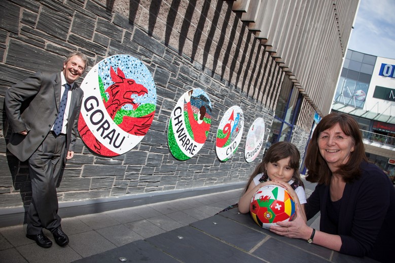 EAGLES MEADOW, WREXHAM   Kevin Critchley,   Jessica Castro,5 and  Lesley Griffiths AM  by the new collage to mark Wales's qualification for the Euro 2016 football championships.