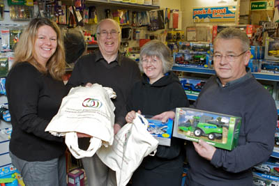 Councillor Sioned Roberts of Porthmadog Town Council and Councillor Selwyn Griffiths, Gwynedd Council member present the re-usable cotton bags to Meryl Pike and Dafydd Williams of W Pike shop in Porthmadog