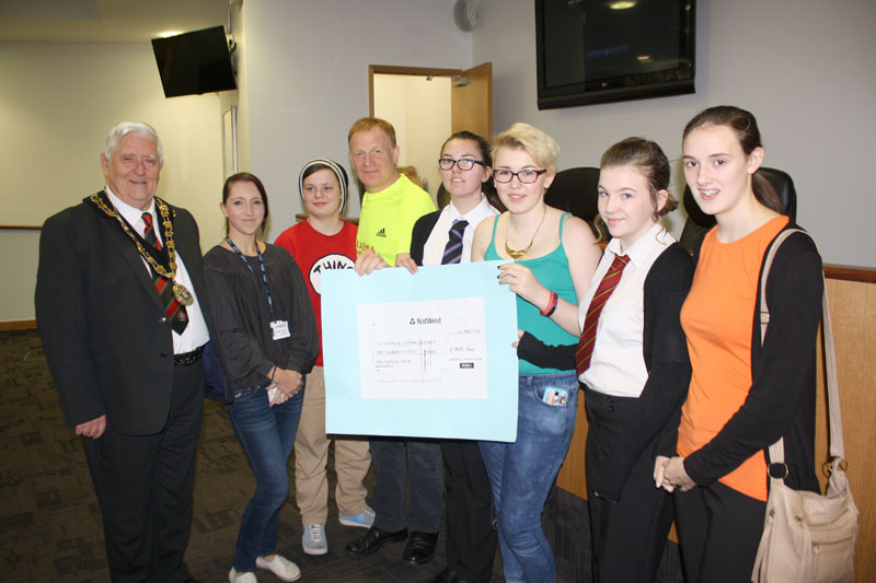 Youngsters from across Caerphilly county borough, together with Mayor of Caerphilly county borough Cllr Michael Gray, present a cheque to runner Mark Lewis Jones