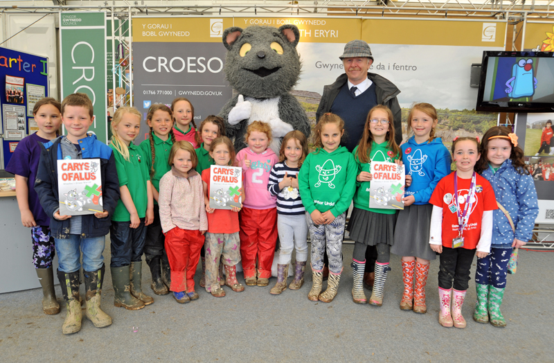 Councillor Gareth Robert with Carys Ofalus and Gwynedd children at the re-launch of the Carys Ofalus book