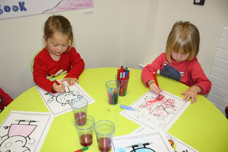 Laila Van Vuuren and Cari Haf Gundersen taking part in the colouring competition at Caerphilly Library