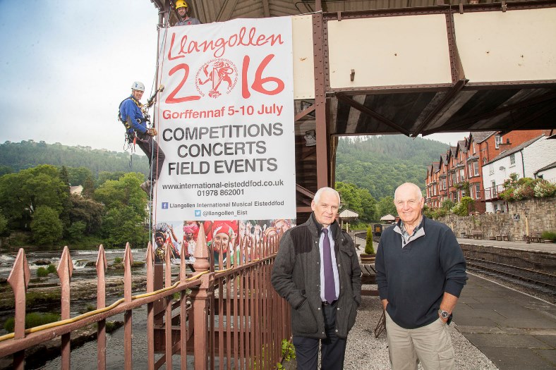 LLangollen Eisteddfod Banners are placed along the railway line in Llangollen with the help from local company R3 Safety & Rescue using their team of Abseilers to secure the banners in place along the railway line. Pictured: Abseiler Paul O'Sullivan secures the banner in place with help from his partner Chris Heath supported by The Eisteddfod marketing manager Ian Lebbon and Llangollen Railway Manager Kevin Gooding