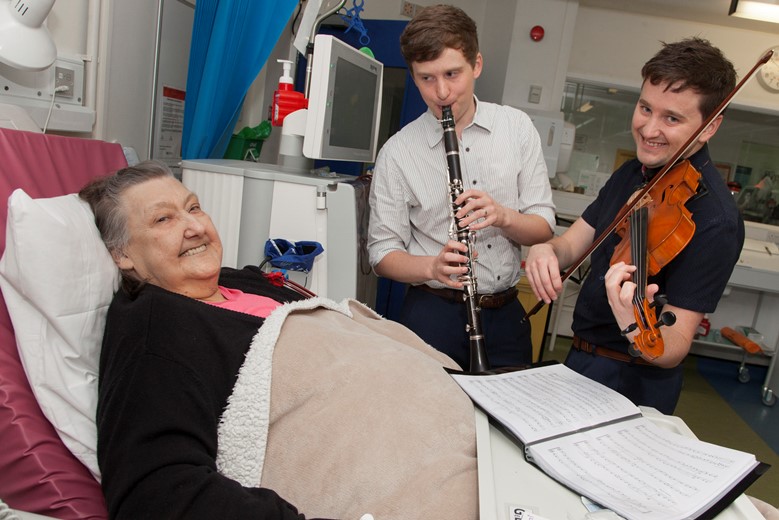 Betsi Cadwaladr University Health Board.... Pictured are Rob and Jon Guy from NEW Sinfonia, who play music at the bedside of  patients receiving kidney dialysis. Patient Gwendoline Evans enjoying her requested piece of music from Jon and Rob Guy.